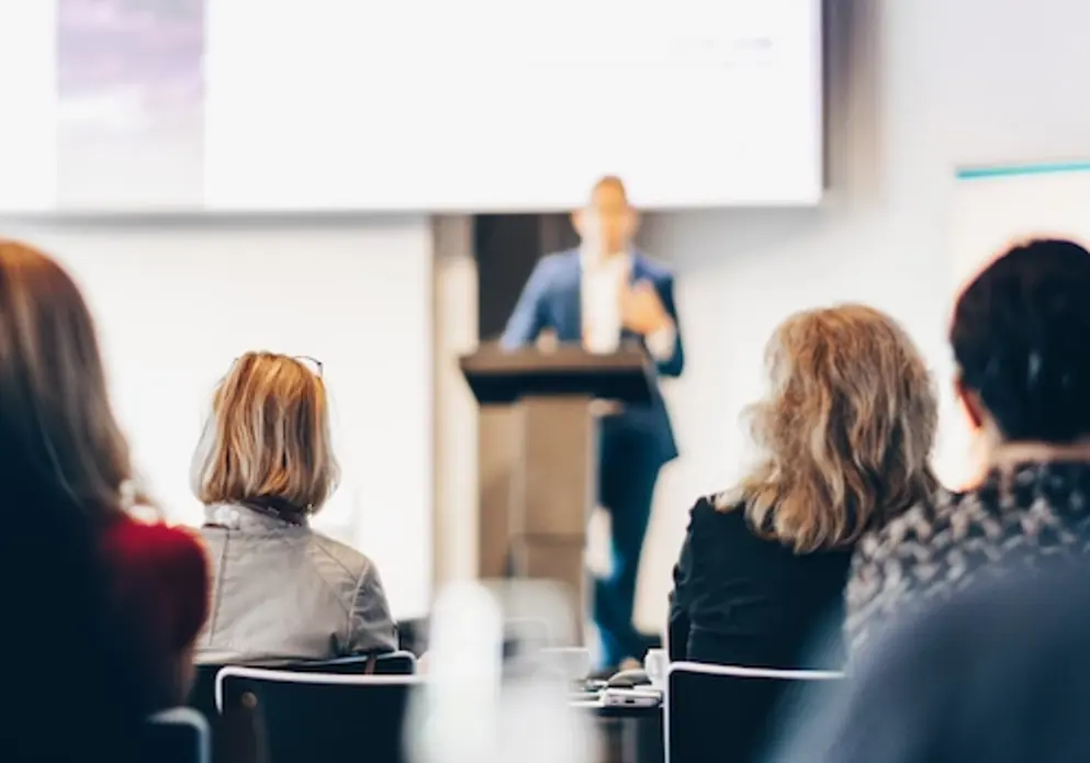 Audience listening to a speaker at a podium during a presentation