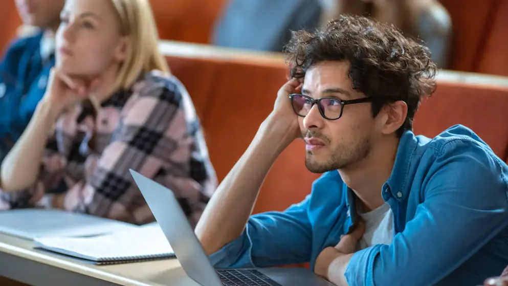 Young man with ADHD trying to focus in a lecture setting