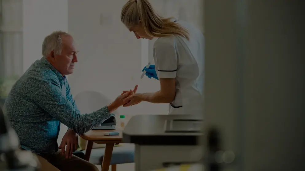 An older man having a blood prick test taken by a young female nurse