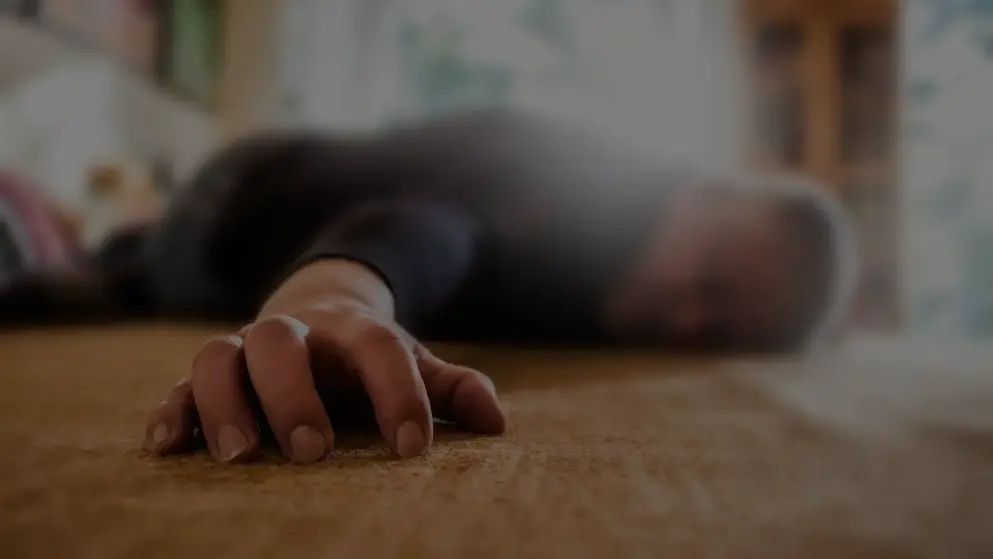 A foreground focus of a man's hand as he lays collapsed after a seizure; his head and body are blurred in the background