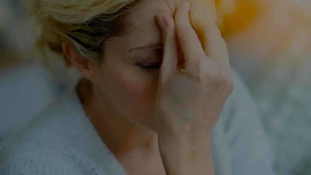 Middle-aged woman suffering from a migraine, holding her head in her hands