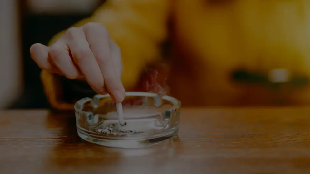 Close up of a hand stubbing out a cigarette in an ashtray