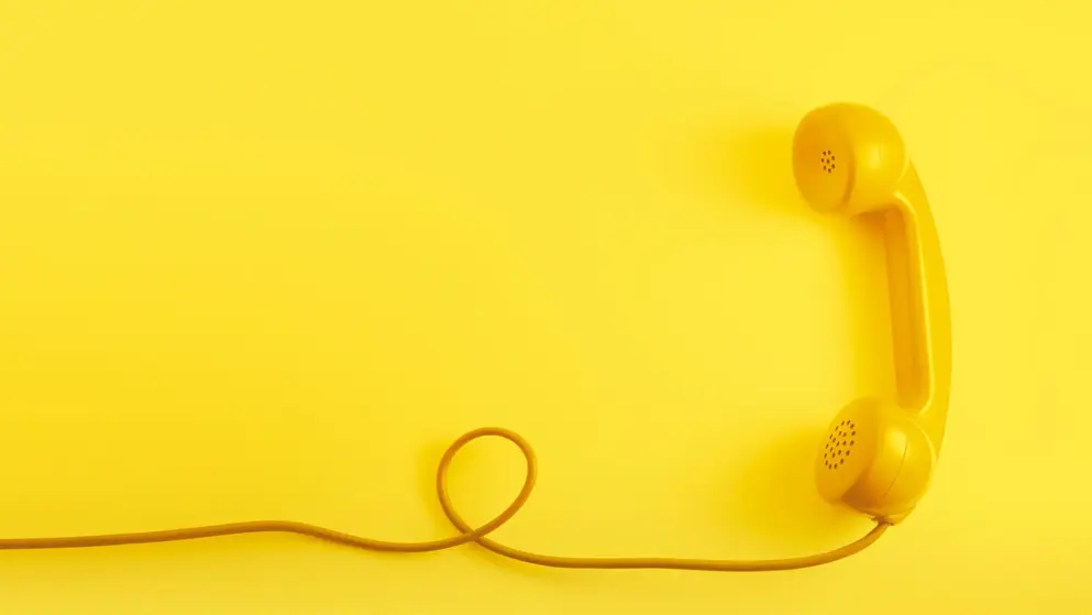 Yellow phone on a yellow background - Feel free to contact us!