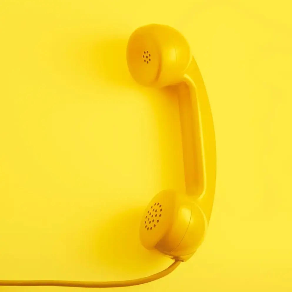 Yellow phone on a yellow background - Feel free to contact us!