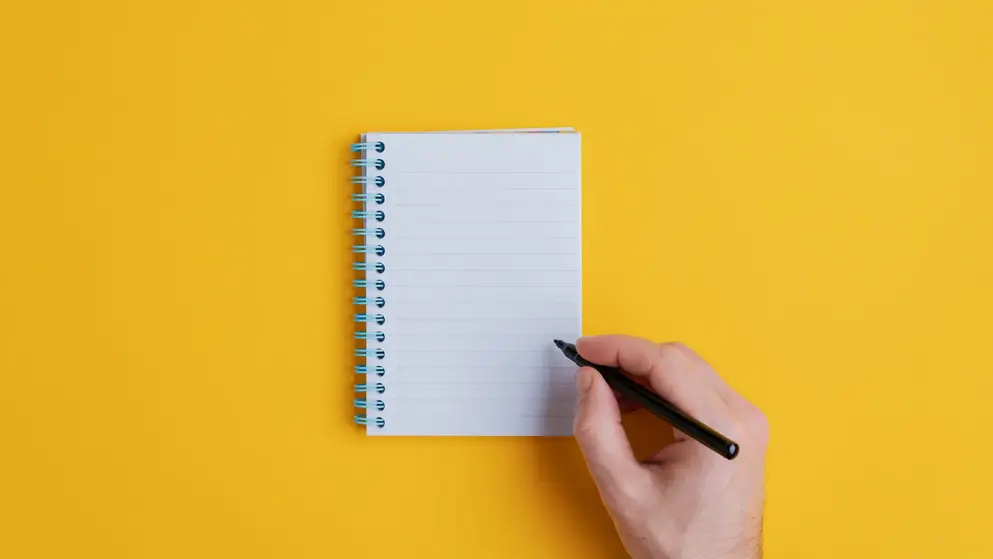 Making notes on a notepad on a yellow background; editorial