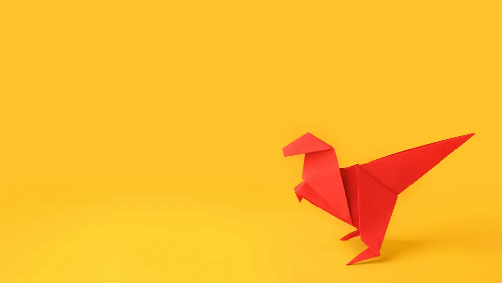 A red origami dinosaur on a yellow background